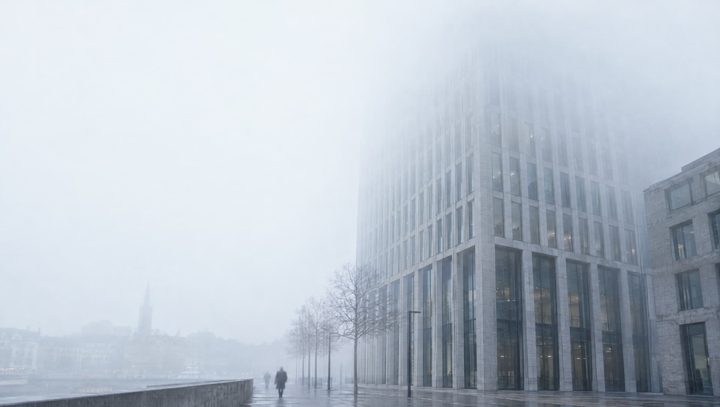 A stone and glass office facade in low cloud