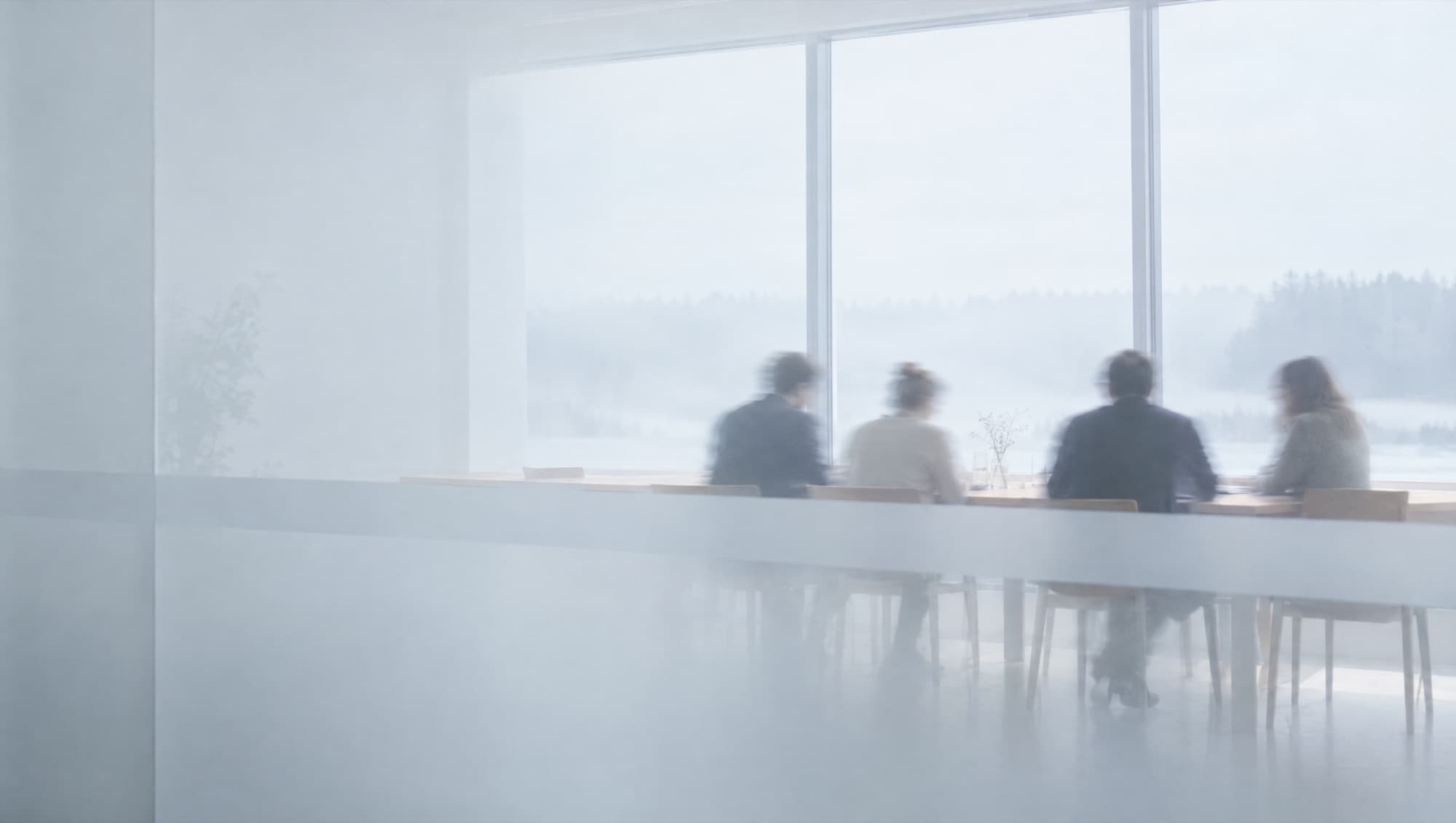 A small team around a table in a bright office, seen through frosted glass