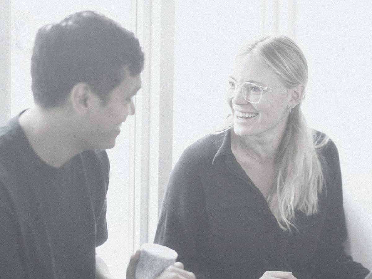 Two colleagues talking and laughing by a window