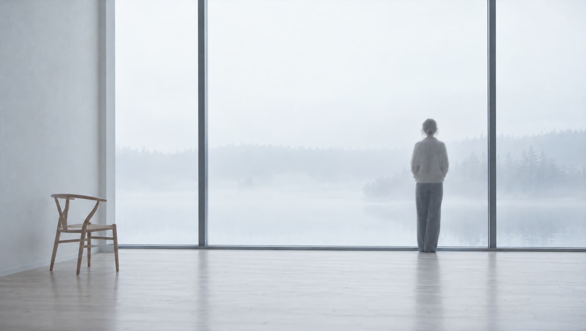 A person at a tall window looking out at fog